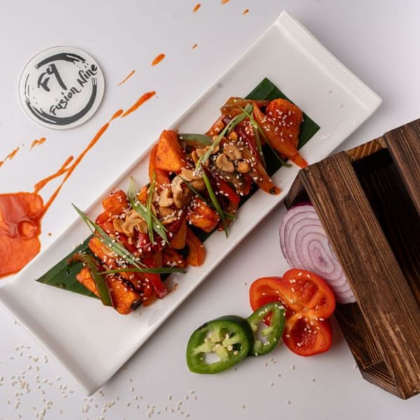 Fusion Nine's Indian dish with paneer, bell peppers, cashews, and sesame seeds on a white platter.