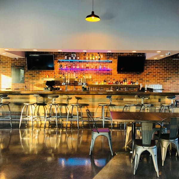 A modern bar area at Fusion Nine with a brick wall, neon lights, and bar stools.