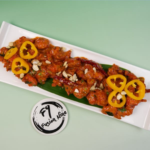 Fusion Nine's orange chicken dish with cashews and yellow peppers on a white plate.