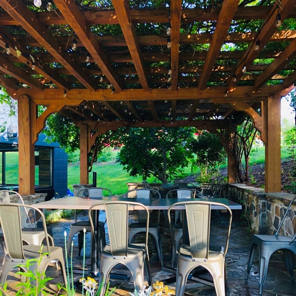 Outdoor dining area at Fusion Nine with a wooden pergola, string lights, and metal chairs.