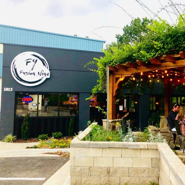 Exterior of Fusion Nine Indian restaurant with a dark facade, outdoor patio, and string lights.